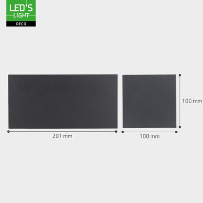 Een moderne, zwarte wandlamp met warm wit licht, bevestigd aan een bakstenen muur. Perfect voor buitenverlichting en een stijlvolle, minimalistische sfeer in tuinen of op veranda’s.