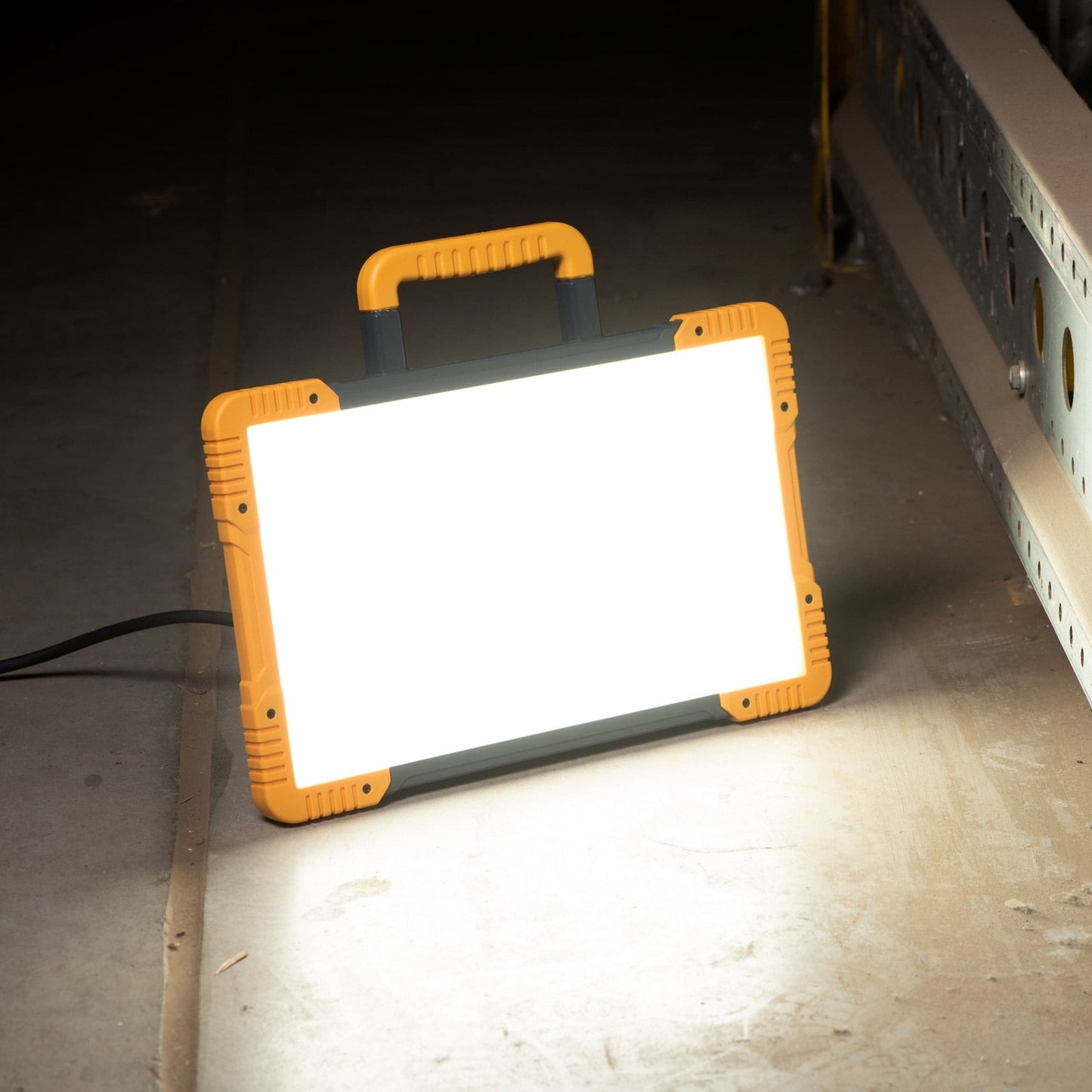 Een robuust, geel en zwart LED-werklicht met een handvat, geschikt voor professionele verlichting op bouwplaatsen en in werkplaatsen. Het licht heeft een witte verlichtingsvlak en de tekst 'LED's LIGHT PRO' is zichtbaar.