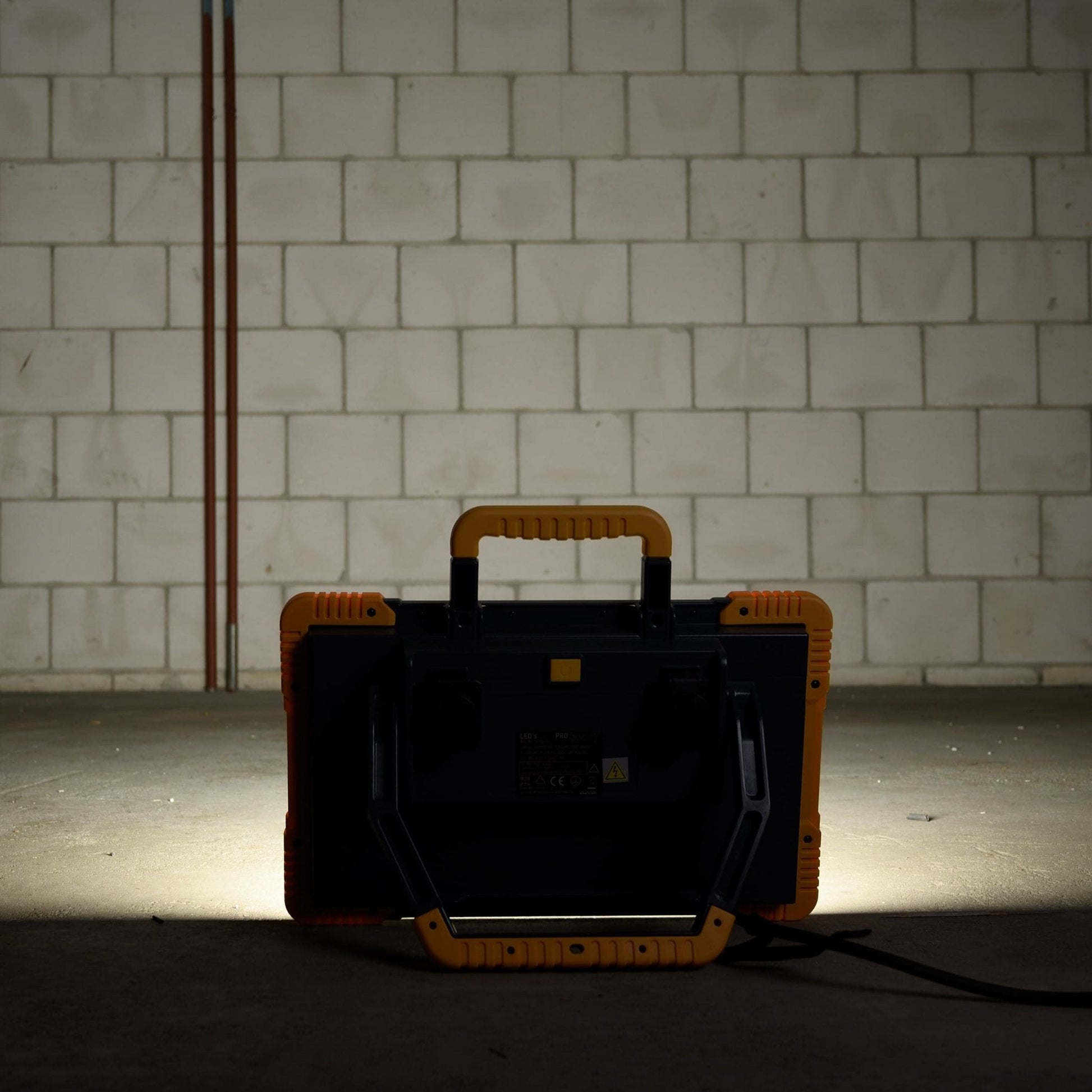 Een robuust, geel en zwart LED-werklicht met een handvat, geschikt voor professioneel gebruik. Het licht heeft een witte verlichtingsvlak en is voorzien van de tekst 'LED's LIGHT PRO'.