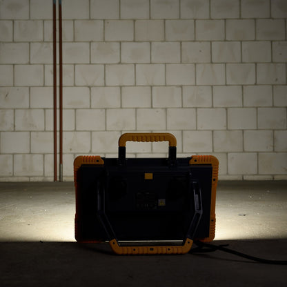 Een robuust, geel en zwart LED-werklicht met een handvat, geschikt voor professioneel gebruik. Het licht heeft een witte verlichtingsvlak en is voorzien van de tekst 'LED's LIGHT PRO'.