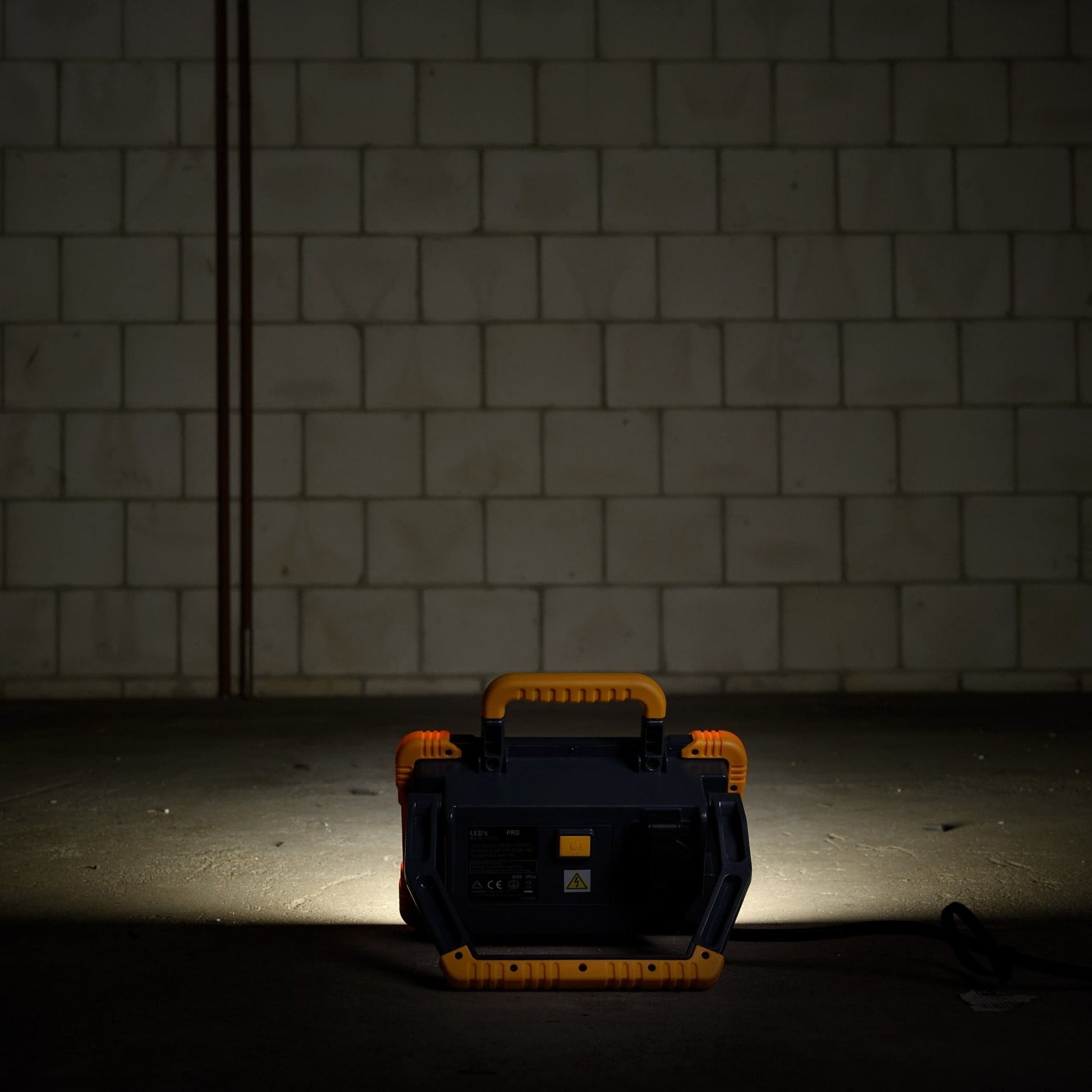 Een robuuste, gele en zwarte LED werklamp met handvat en kabel, geschikt voor professioneel gebruik in workshops of op bouwplaatsen.