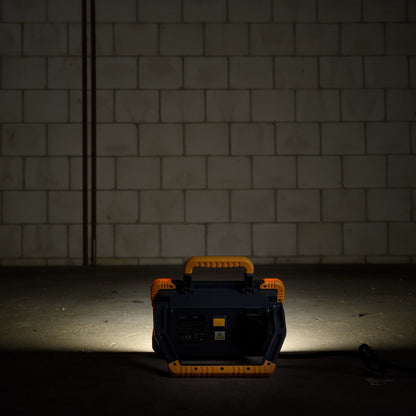 Een robuuste, gele en zwarte LED werklamp met handvat en kabel, geschikt voor professioneel gebruik in workshops of op bouwplaatsen.