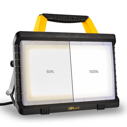 Zwart LED-verlichtingsapparaat met gele handgreep en stekker, geschikt voor werken in donkere ruimtes. Robuust ontwerp met transparante lichtplaat en merknaam LED’s work.