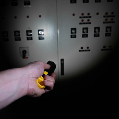 Zwarte LED-lamp met gele handgreep en verstelbare arm, geschikt voor werken in donkere ruimtes. Ideaal voor reparaties, onderhoud en andere handige taken waar helder licht nodig is.