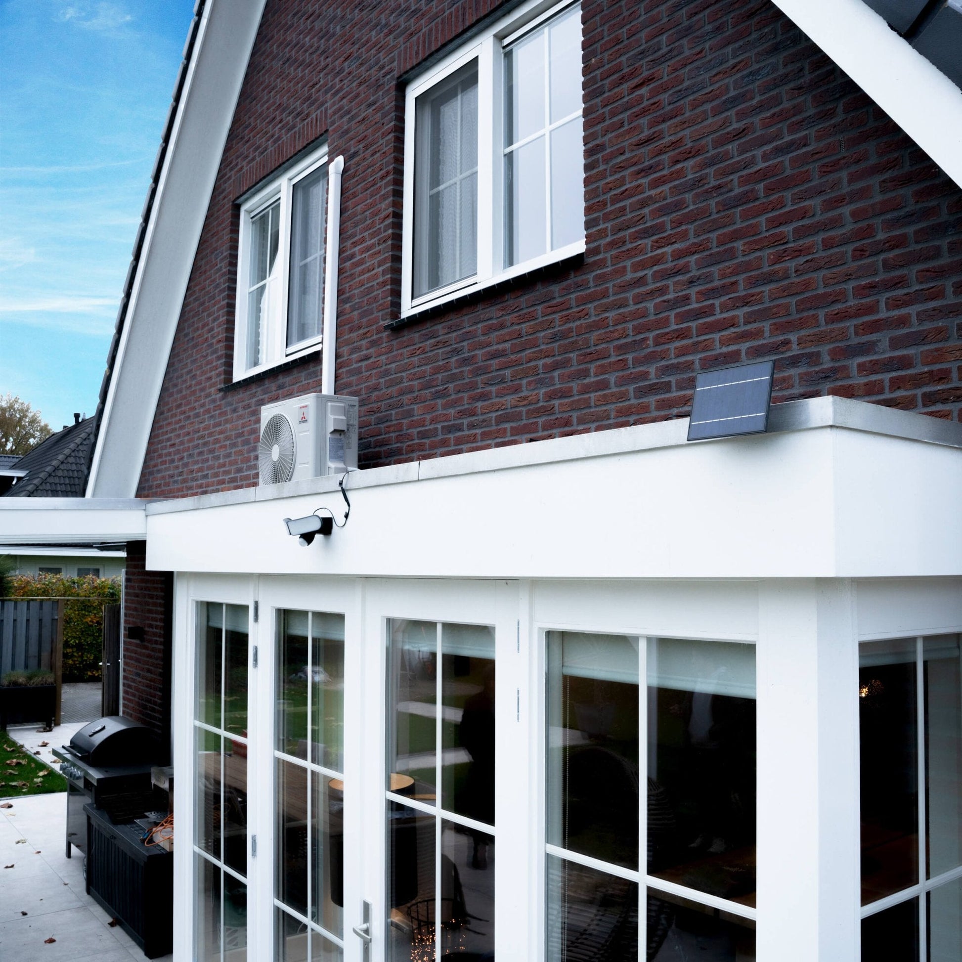 Zwarte zonne-licht met bewegingssensor, geïnstalleerd op een donkere bakstenen muur. Twee heldere LED-lampen en een zonnepaneel voor nachtverlichting in de tuin of op de veranda.