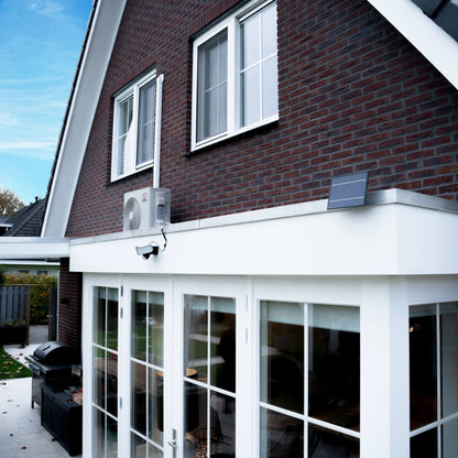 Zwarte zonne-licht met bewegingssensor, geïnstalleerd op een donkere bakstenen muur. Twee heldere LED-lampen en een zonnepaneel voor nachtverlichting in de tuin of op de veranda.