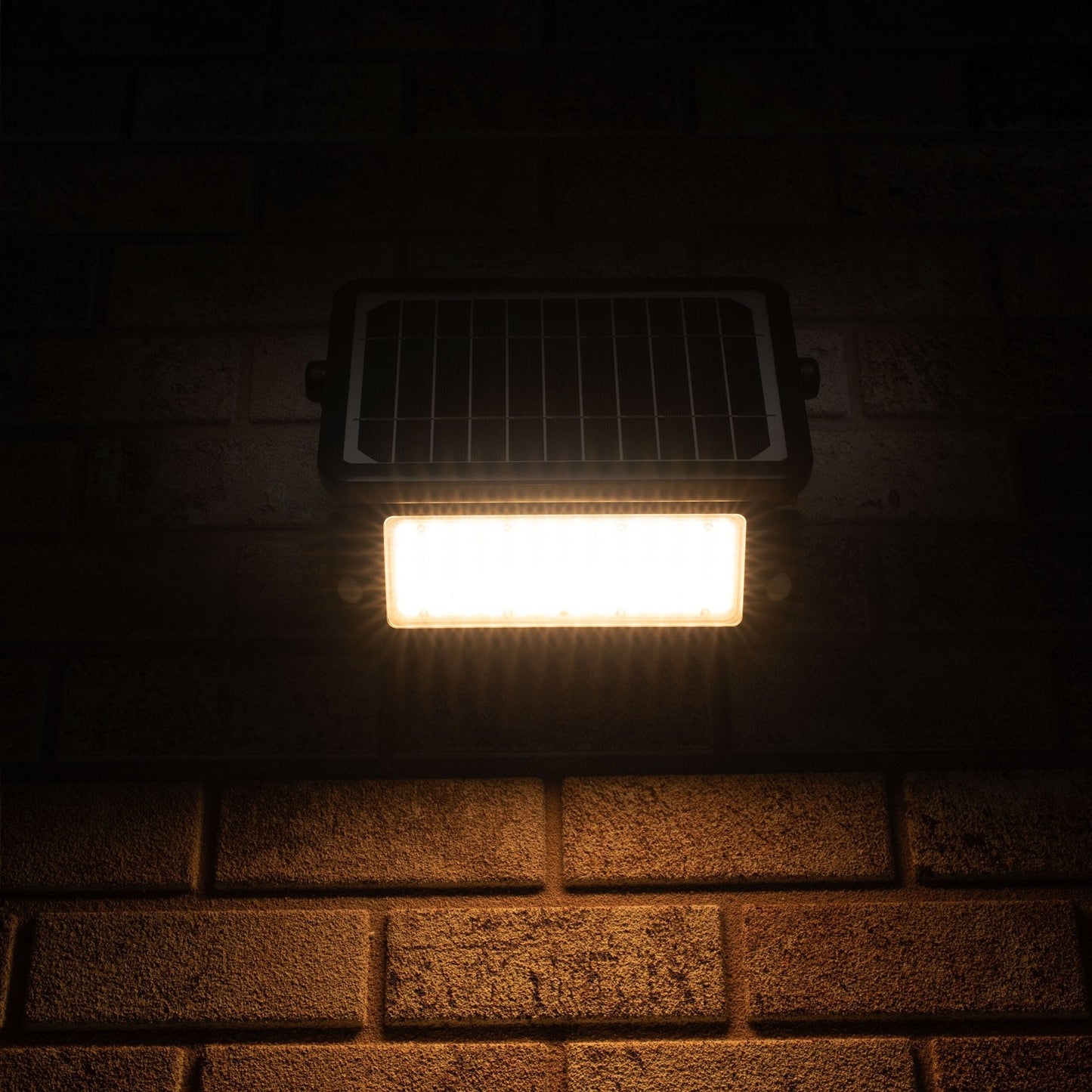 Zwarte zonnepanelenverlichting met warm wit licht, gemonteerd op een bakstenen muur. Ideaal voor buitenverlichting en tuinverlichting, met zichtbare LED’s en zonnecel.
