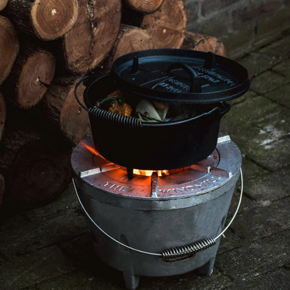 Zwarte gietijzeren Dutch oven met afneembare deksel en metalen draadhandvat, geschikt voor kampvuur en barbecue. Robuust ontwerp met driepoot onderzijde voor stabiele kookopstelling.