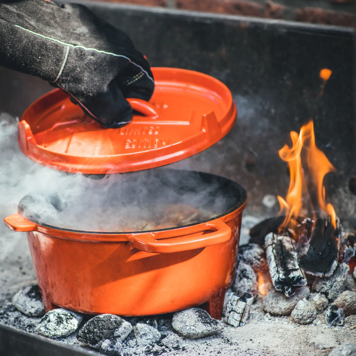Oranje kookpan met deksel van The Windmill, een beperkte editie gemaakt van glanzend gestookt metaal. Het deksel draagt het merk en de tekst 'Limited Edition', perfect voor koken op de open haard of in de oven.