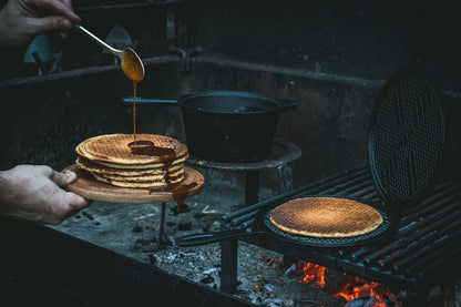 Zwarte, ronde wafelpan met opengeslagen deksel en gestructureerde grillvlakken voor perfecte wafels. Gemaakt van koolstofstaal, geschikt voor wafelbakken en grillen.