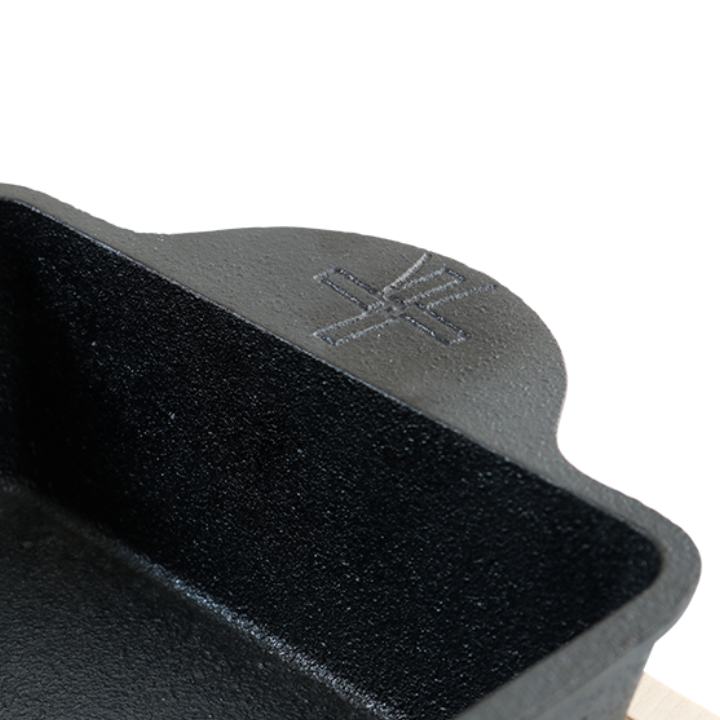 Zwart gietijzeren bakje met handvatten en het merklogo, geschikt voor oven- en grilltoepassingen. Robuust en geschikt voor het bakken van taart en brood.