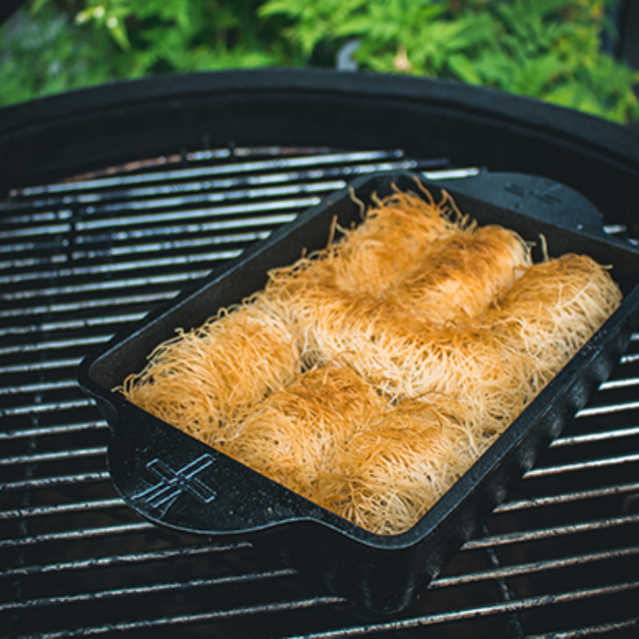 Zwart gietijzeren bakvorm met handvatten en het merklogo, geschikt voor oven- en grilltoepassingen. Robuust ontwerp voor professionele en thuiskeuken gebruik.