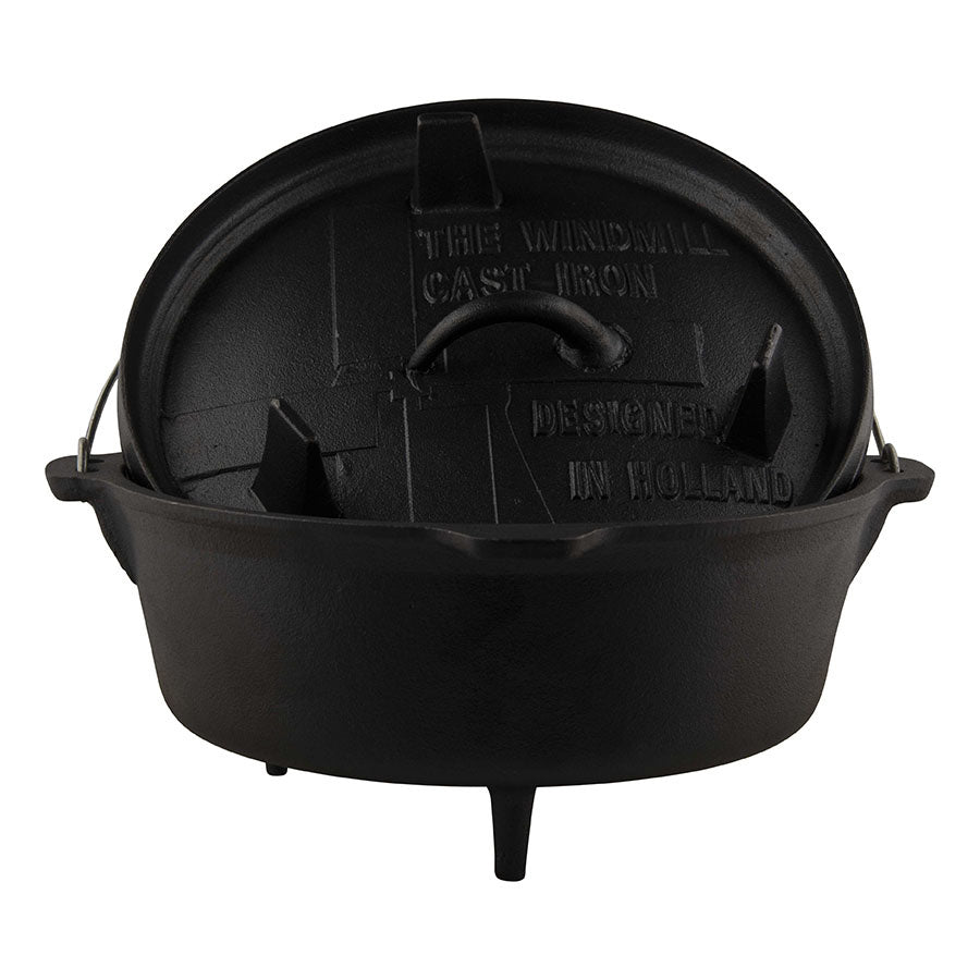 Zwarte cast iron Dutch oven met afdekking, gietijzeren constructie en handvat, ontworpen in Holland voor kookplezier op kamp of in de keuken. Geschikt voor outdoor koken en professionele keukengereedschap.