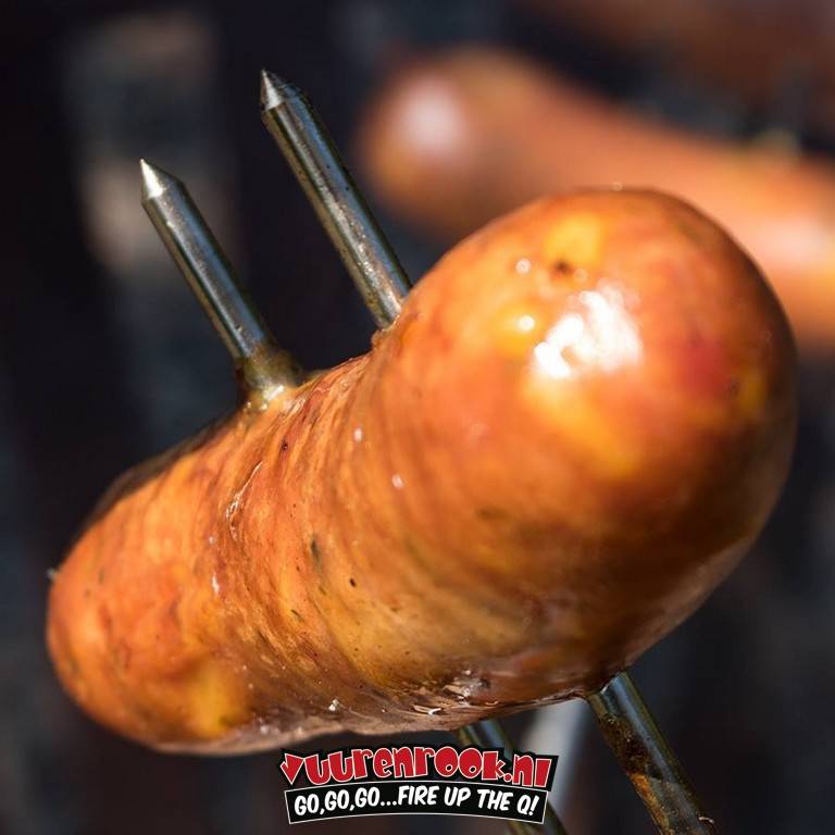 Een zwart, metalen barbecue spies met een dubbele vork aan één kant en een handvat aan de andere kant, geschikt voor het grillen van vlees of groenten op een open vuur.