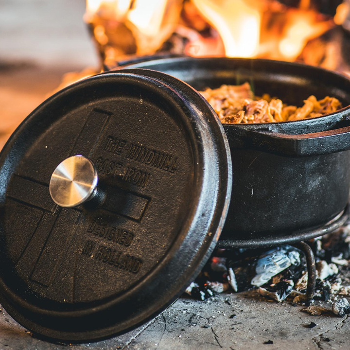 Zwarte kookpan van gietijzer met afdekking, voorzien van handvatten en het merklogo. Geschikt voor hoge hitte en langdurig koken, ideaal voor stoofpot en braadpan.