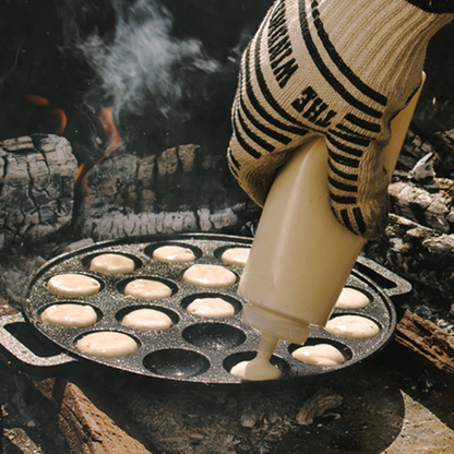 Zwarte, ronde cast-iron pannen met twaalf bolvormige gaten, voor het bakken van traditionele Japanse takoyaki. Met handvatten voor gemakkelijk hanteren en hoge hittebestendigheid.