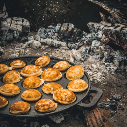 Zwarte, ronde cast iron pannetje met twaalf bolvormige gaten, geschikt voor het bakken van traditionele Japanse takoyaki. Met handvatten aan weerszijden voor gemakkelijk hanteren.