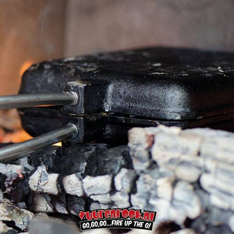 Een zwarte, vierkante roosterplaat met een ingegraveerd kruis, verbonden aan een lichtbruine, geribbelde houten handgreep via een metalen stang, geschikt voor gebruik bij barbecueën en buitenkooktoestellen.