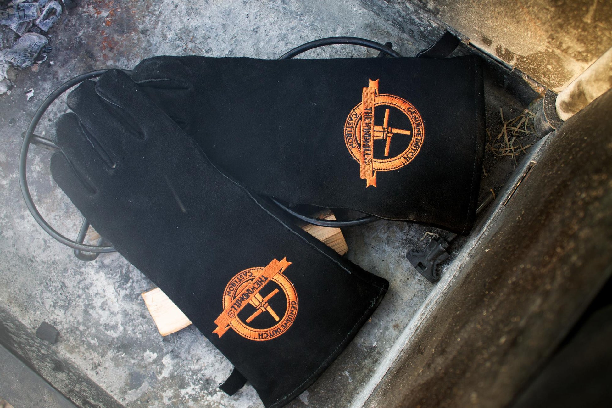 Zwarte leerhandschoenen met opgestikte goudkleurige logo, geschikt voor werken met warmte en hoge temperatuur. Zichtbare naadwerk en zachte textuur voor betere grip en comfort.