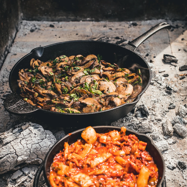 Zwarte kookpan van gietijzer met gladde binnenkant en lang handvat, geschikt voor grillen en bakken. Robuust ontwerp voor elke kookplaat of open haard.