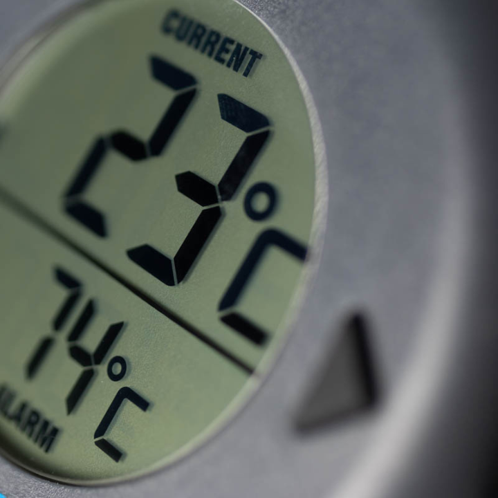 Zwart ronde BlueDOT thermometer met digitale display, toont huidige temperatuur 76°F en alarm 165°F. Bluetooth-icoon en bedieningsknoppen zichtbaar voor gebruik in keuken of op kookplaat.