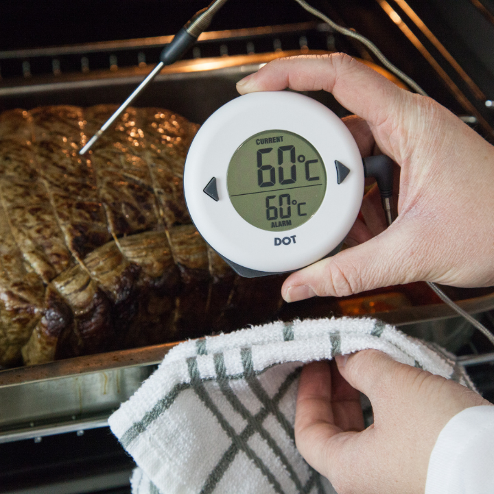 Een witte, ronde digitale thermometer met zwarte knoppen, weergevend huidige temperatuur 34°C en alarm 75°C. Geschikt voor keuken- en badkamergebruik met duidelijke, leesbare display.