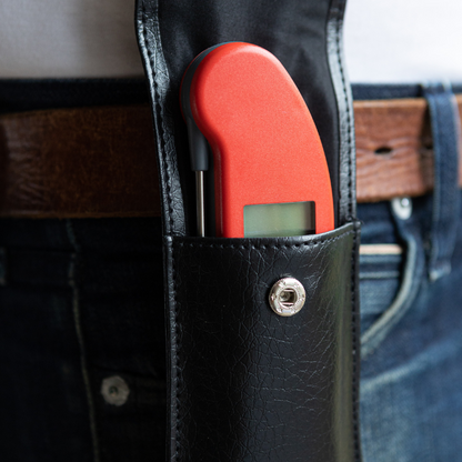 Zwart kunstleer portemonnee met metalen knop, geschikt voor dagelijks gebruik. Compacte, elegante tas met glad oppervlak en praktische sluiting voor mobiele telefoon of kleine objecten.
