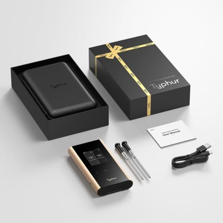 Typhur Smart Thermometer met goudkleurige rand en zwart scherm, inclusief twee metalen sensorstokjes en een zwarte leerachtige hoes. Geleverd in een zwarte doos met gouden band, ideaal voor precisieke keukengereedschap.