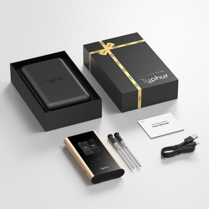 Typhur Smart Thermometer met goudkleurige rand en zwart scherm, inclusief twee metalen sensorstokjes en een zwarte leerachtige hoes. Geleverd in een zwarte doos met gouden band, ideaal voor precisieke keukengereedschap.