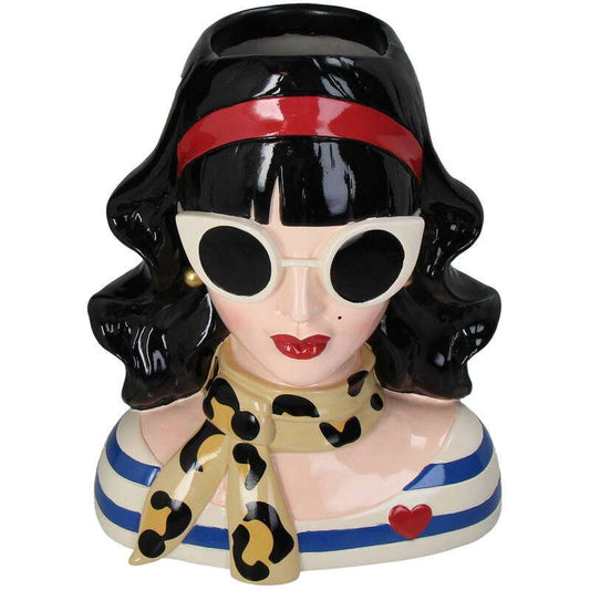 Een glanzende keramische theepot in de vorm van een vrouw met zwart haar, rode band, witte zonnebril en luipaardprint sjaal. Perfect voor een retro koffietafel of als decoratief item in een vintage interieur.