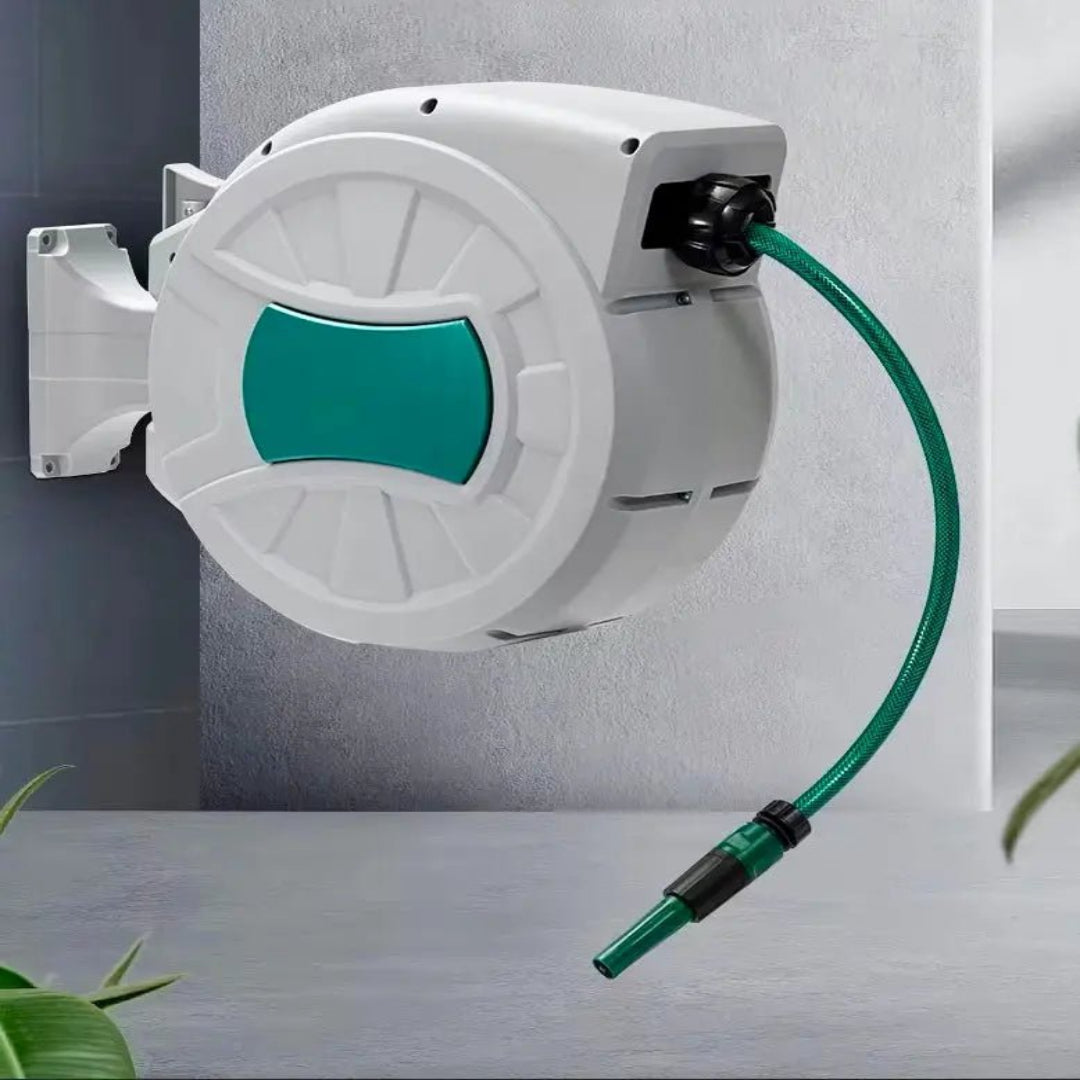Een witte wandmonteerde tuinslangrol met groene accenten en een flexibele slang, geschikt voor tuinwatering. De slang is uitgerold en eindigt in een groen handvat voor gemakkelijke gebruik.