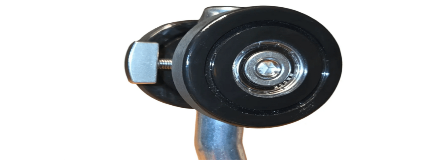 Zwarte metalen handgreep met oranje grip en twee grote wielen, geschikt voor zware kasten of industriële kasten. Geschikt voor gebruik in keukens, garages of opslagruimtes.
