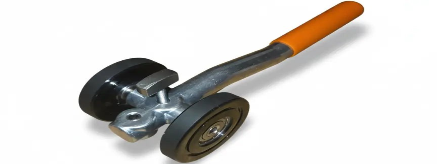 Zwarte, metalen handgreep met oranje grip en twee grote wielen voor gebruik bij zware kasten of meubels. Geschikt voor het verplaatsen van zware objecten in huishoudelijk of industriële omgevingen.