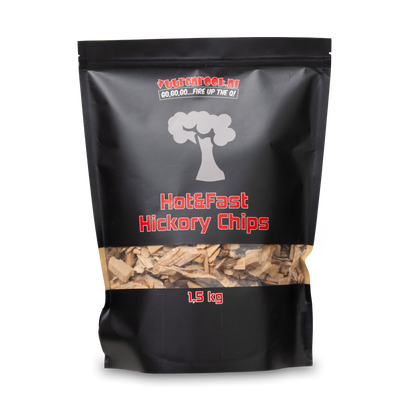Een zwarte zak met transparante onderkant, gevuld met hickory chips voor barbecue. Het merk 'Vuurenrook.nl' en de tekst 'Hot&Fast Hickory Chips 1,5 kg' zijn duidelijk zichtbaar.