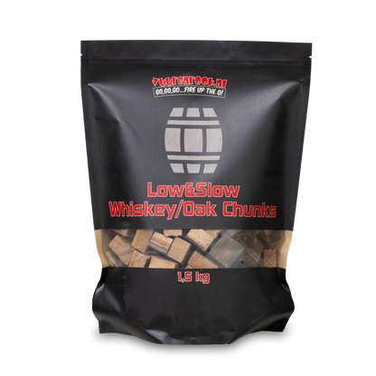 Een zwarte zak met transparante onderkant bevat 1,5 kg whiskey/oak chunks, geschikt voor barbecue en grillen. De tekst op de verpakking vermeldt ‘Low&Slow’ en het merk ‘Vuurenrock.nl’.