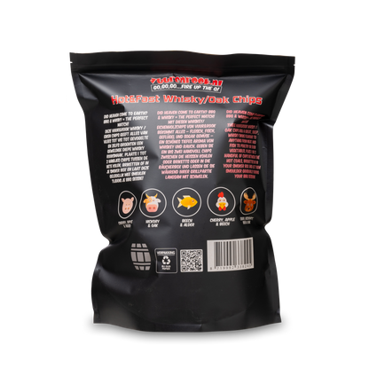 Een zwarte zak met transparante onderkant bevat 1,5 kg whiskey/oak chunks voor barbecue. De verpakking toont een houten vatlogo en rode tekst voor grillen en roosteren.