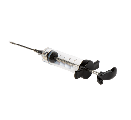 De Meat Injector is een transparante, glazen spuit met metalen naald, verpakt in zwart blisterpapier met rood logo. Geschikt voor vleesinjectie bij barbecue en grillen.