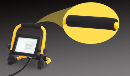 Een robuuste, gele en zwarte LED werklamp met verstelbare arm en zwart rubberen handvat, geschikt voor gebruik in werkplaatsen of bij nachtelijke bouwactiviteiten.